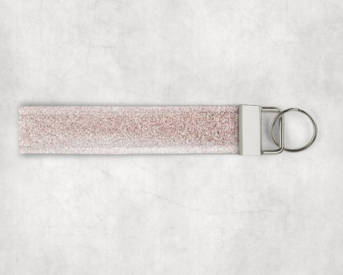 A faux leather wristlet made of a pink fine glitter fabric. The hardware cap is a metallic silver color with a keyring on the end.